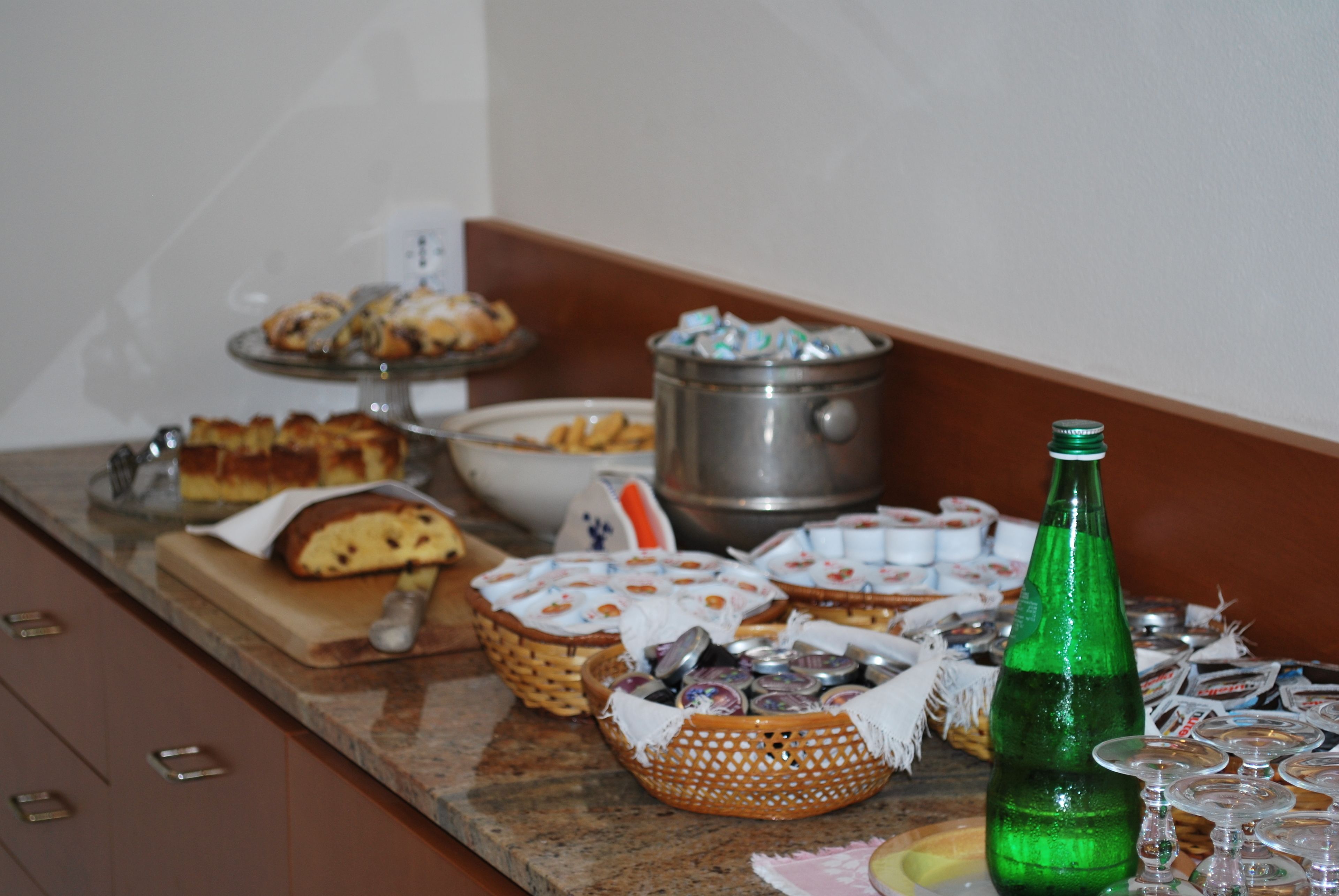 A buffet table with various food items and a green bottle.