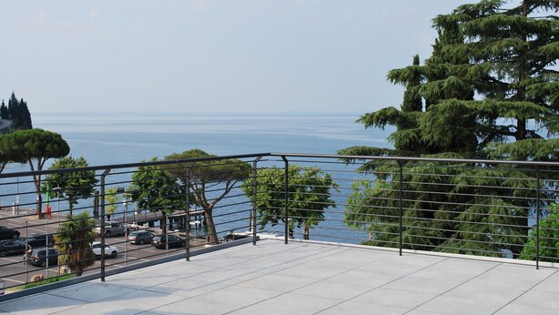 A terrace with a view of the sea and trees. - Hotel Europa (Garda)