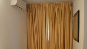 A small room with a bed, a table, and an air conditioning unit. - L'Aquarius Marina 2000 (Douala)