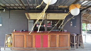 A bar area with a wooden counter, stools, and hanging decorations. - L'Aquarius Marina 2000 (Douala)