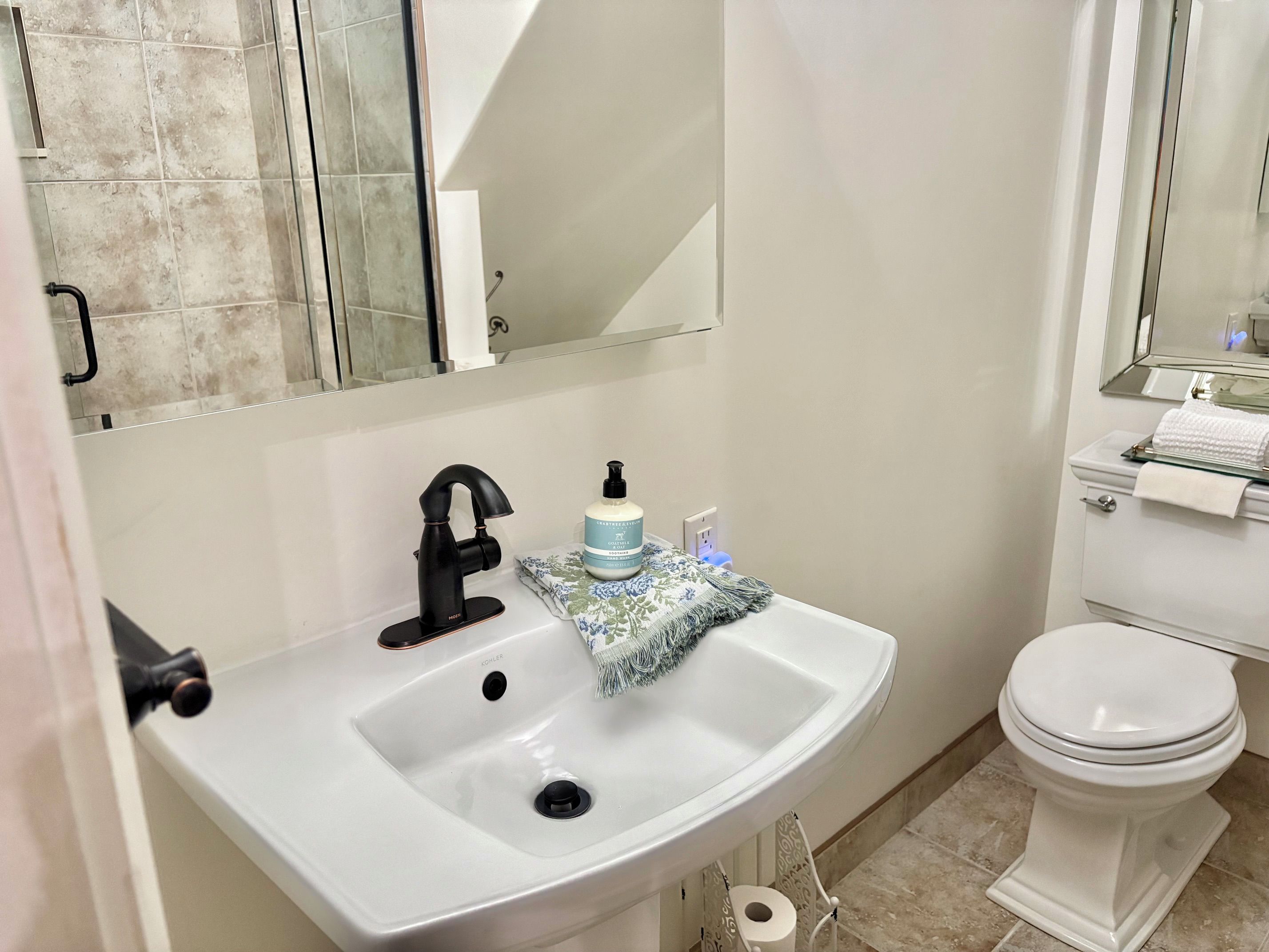 A bathroom with a white sink, black faucet, and a toilet.