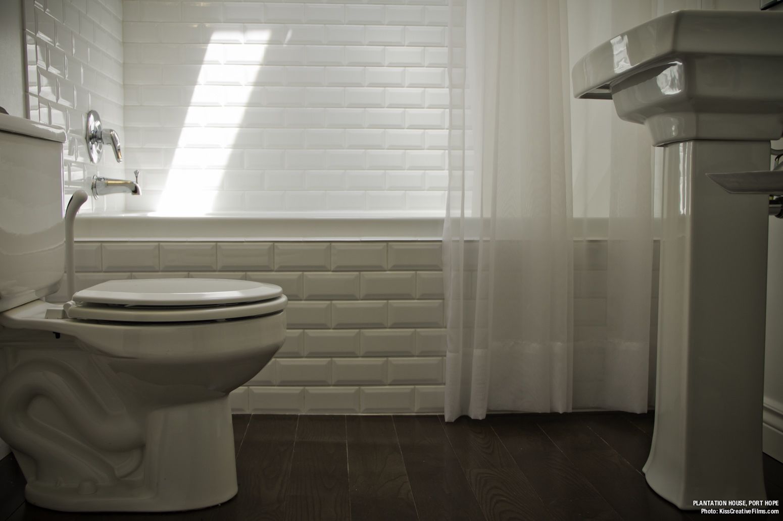 Un bany amb vàter, un lavabo i una finestra amb persianes.