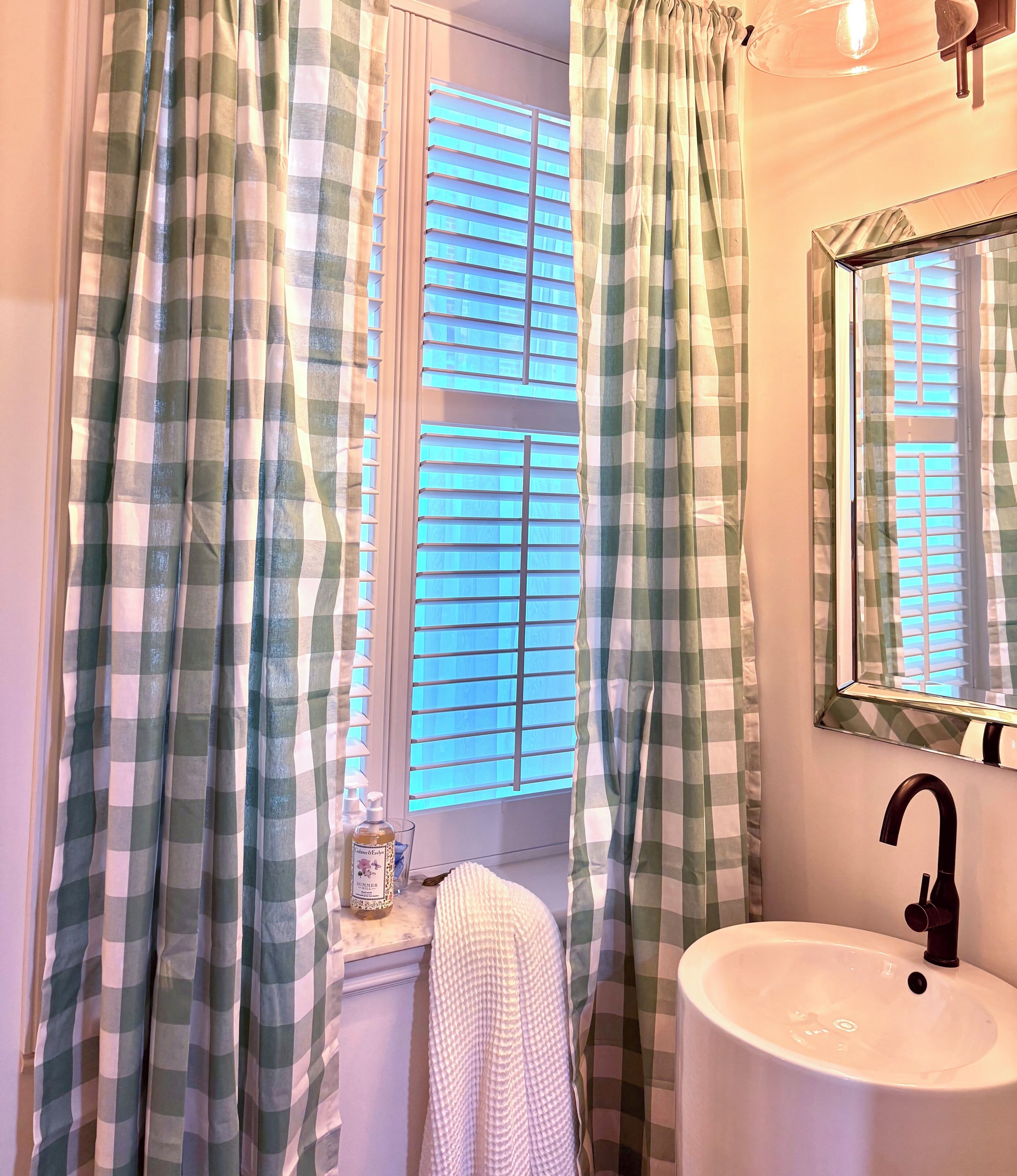 Un baño con ventana, un lavabo y un espejo.
