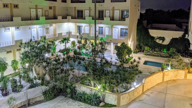 Un hotel de varios pisos con balcones, una piscina y jardines bien cuidados.