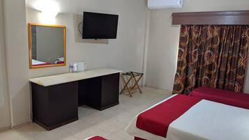 Una habitación de hotel con cama, escritorio, silla, televisión, espejo y cortinas.