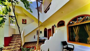 Um interior com vários níveis, incluindo uma escadaria, área de jantar e uma janela com cortinas.