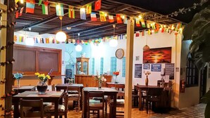 Restaurante com mesas e cadeiras de madeira, um relógio e uma parede com bandeiras.