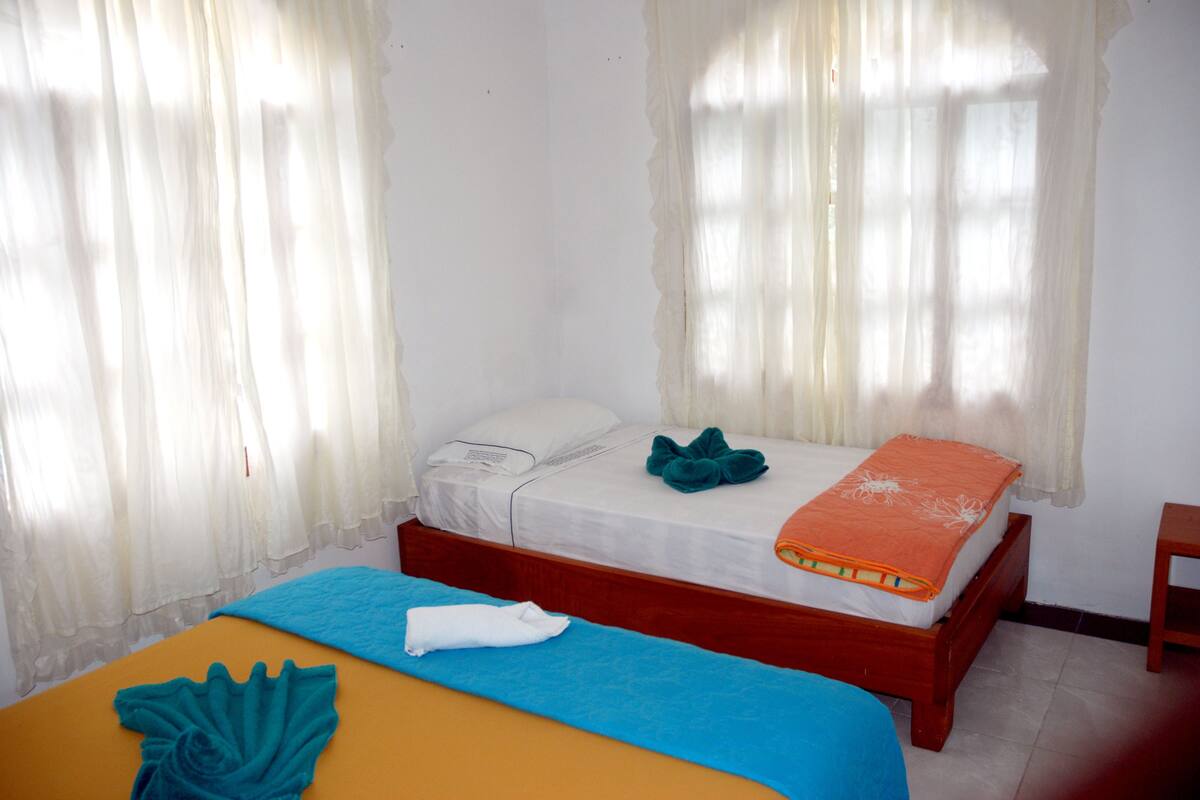 Une chambre avec deux lits, l’un recouvert d’une couvre-lit bleue et l’autre d’une couvre-lit orange.