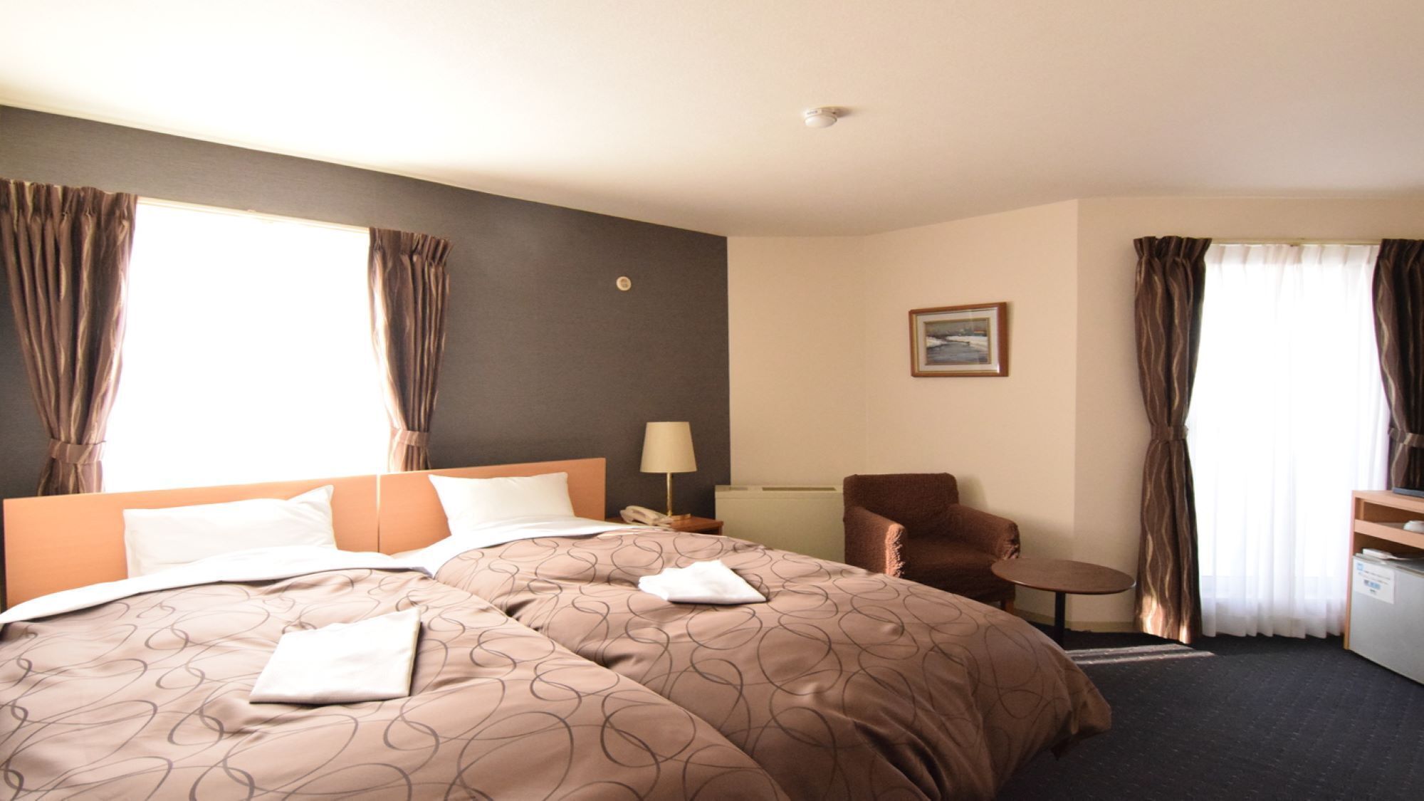 Ein Hotelzimmer mit einem großen Bett, einem Sessel, einem kleinen Tisch und einem Gemälde an der Wand.