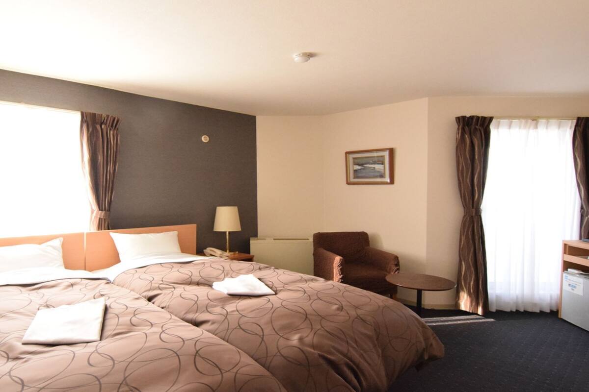 Ein Hotelzimmer mit einem großen Bett, einem Sessel, einem kleinen Tisch und einem Gemälde an der Wand.
