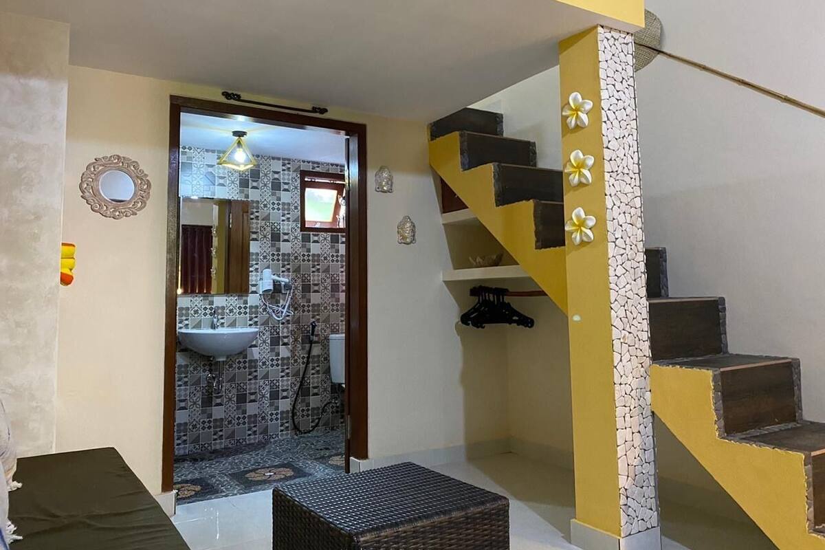 A room with a staircase, a sink, and a mirror.