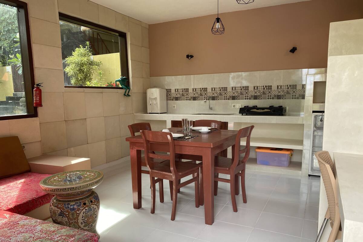 A dining area with a wooden table and chairs, a patterned table runner, and a small decorative vase.