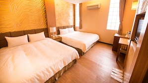 Une chambre d’hôtel avec deux lits, un plancher en bois, un bureau, une chaise, un appareil de climatisation et une fenêtre avec des rideaux.