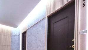 Un couloir avec une porte sombre, des murs de couleur claire et un plancher en bois.