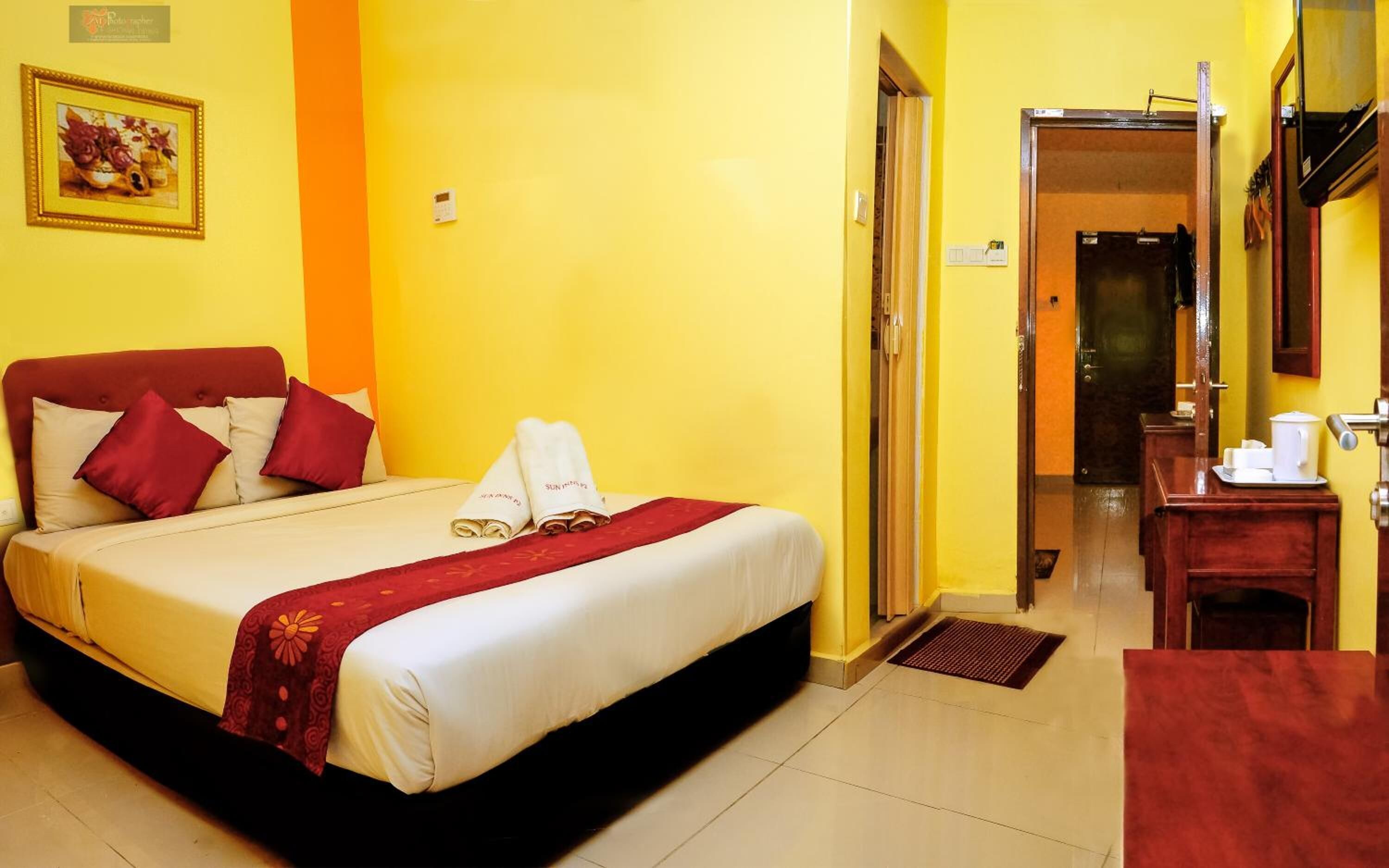 A hotel room with a bed, a desk, and a bathroom visible through an open door.