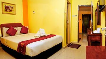 A hotel room with a bed, a desk, and a bathroom visible through an open door.