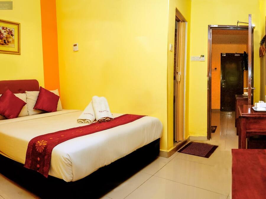 A hotel room with a bed, a desk, and a bathroom visible through an open door.