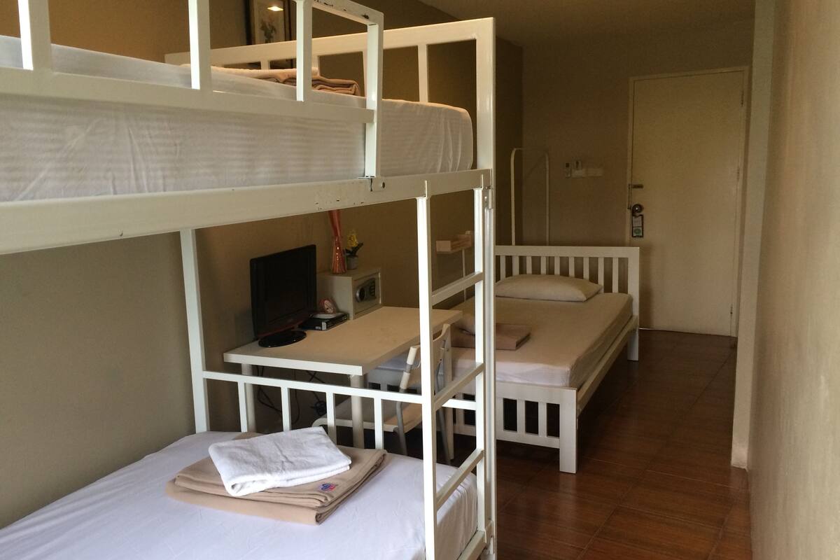 A bunk bed room with a desk and a television.