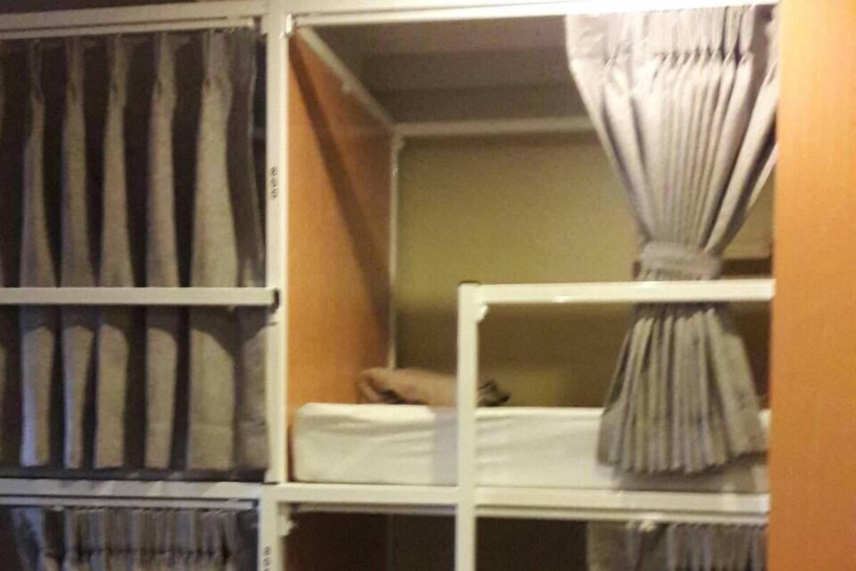 A storage closet with multiple shelves and hanging storage for curtains.