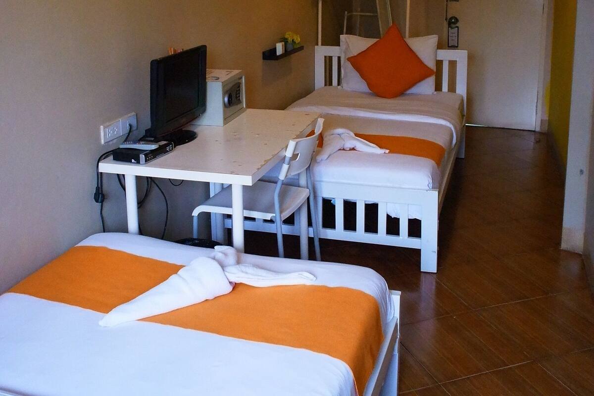 A hotel room with two beds, a desk with a computer, and a television.