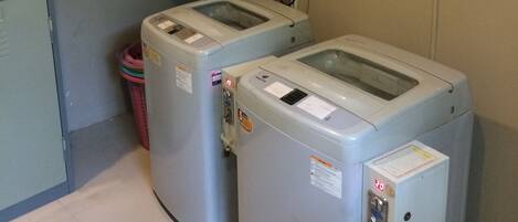 A laundry room with two front-loading washing machines and a top-loading dryer.