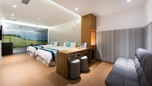 A modern hotel room with a large bed, a desk, two ottomans, a sofa, and a large window with a scenic view. - Garden Spring Hotel (Jiaoxi)