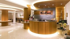 A hotel reception area with a wooden reception desk, a panda statue, and a sign with Chinese characters. - Garden Spring Hotel (Jiaoxi)