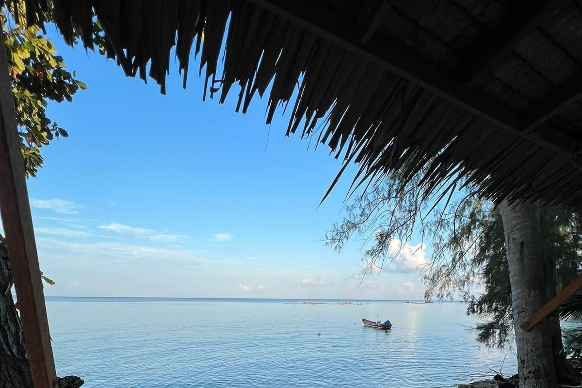 A beach view with a thatched roof structure, a sandy beach, and calm sea.