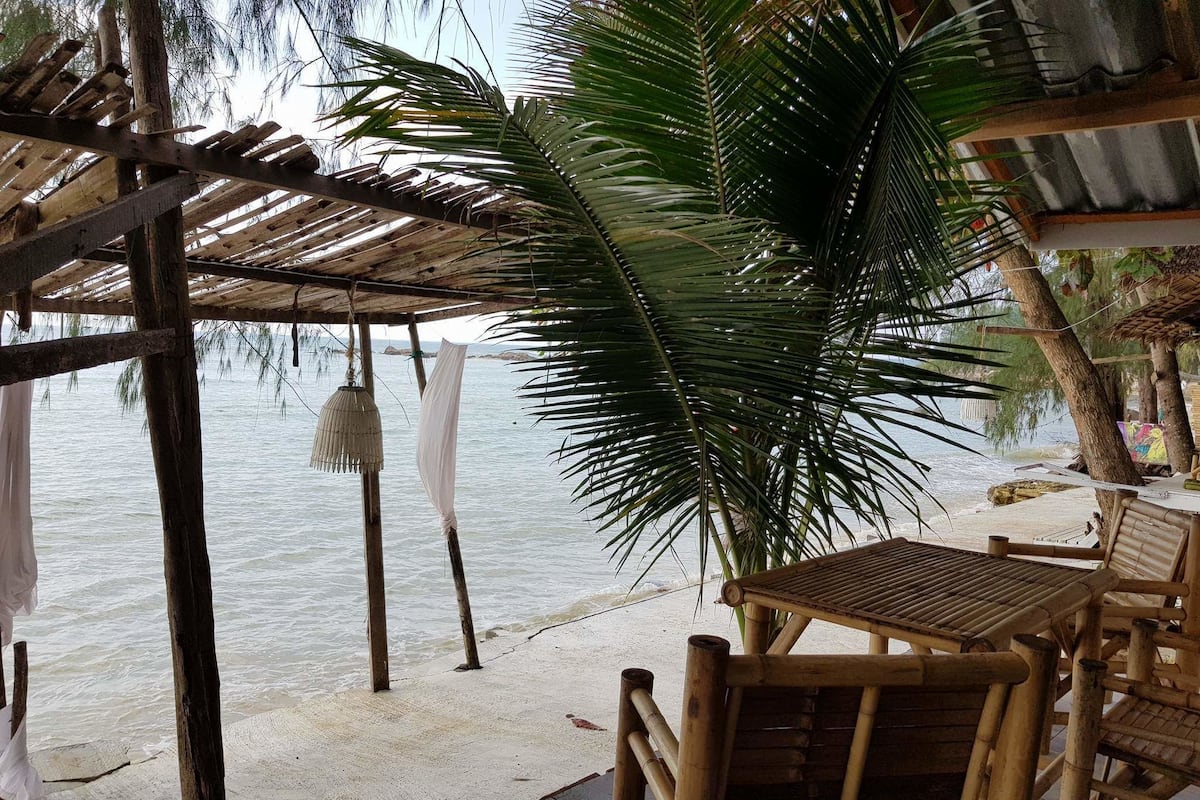 A beachside wooden structure with a table and chairs, overlooking the sea.