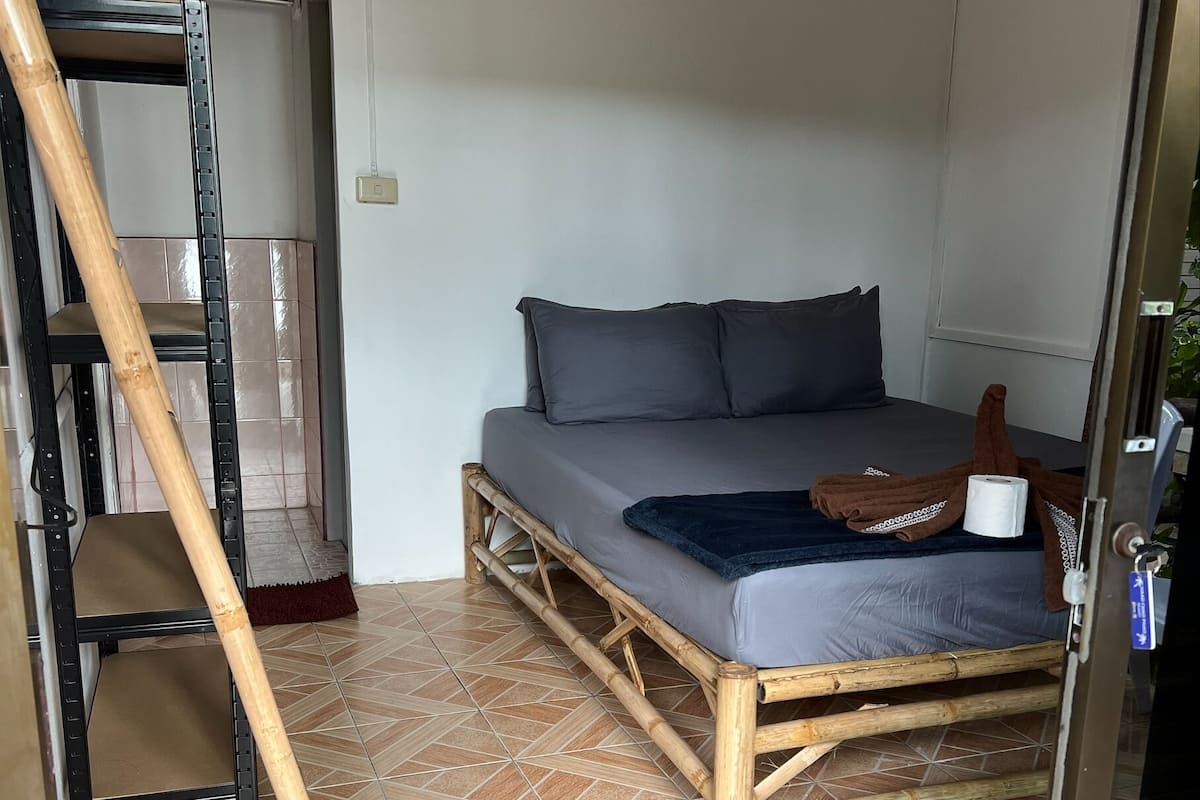 A room with a bed, a wooden ladder, and a tiled floor.