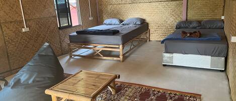A room with two beds, a small table, and a patterned rug.