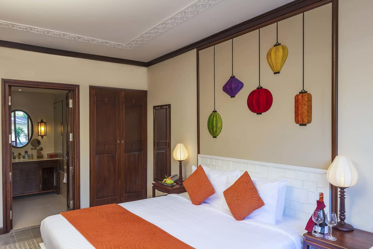 Een hotelkamer met een bed, nachtkastjes, een spiegel en een wand met lantaarns.