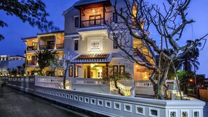 Un edificio de varios pisos con un balcón, un letrero que dice "COZY VILLA" y una entrada bien iluminada.