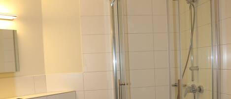 A bathroom with a glass-enclosed shower, a white sink, and a toilet.