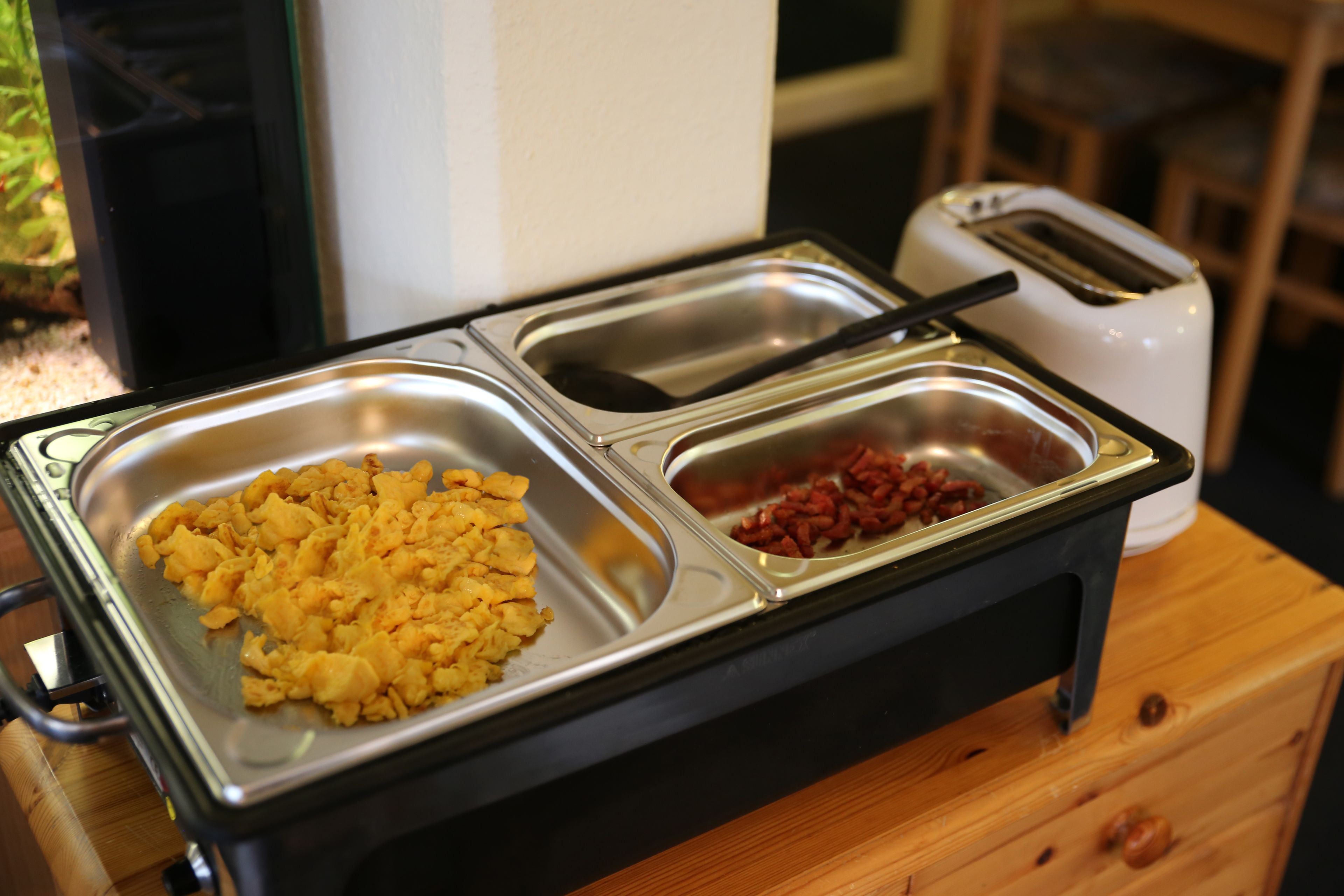 A buffet setup with scrambled eggs and red beans on a stainless steel tray.