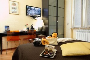 A hotel room with a bed, a desk with a computer, a chair, a lamp, and a window with curtains. - Gala B&B (Rome)