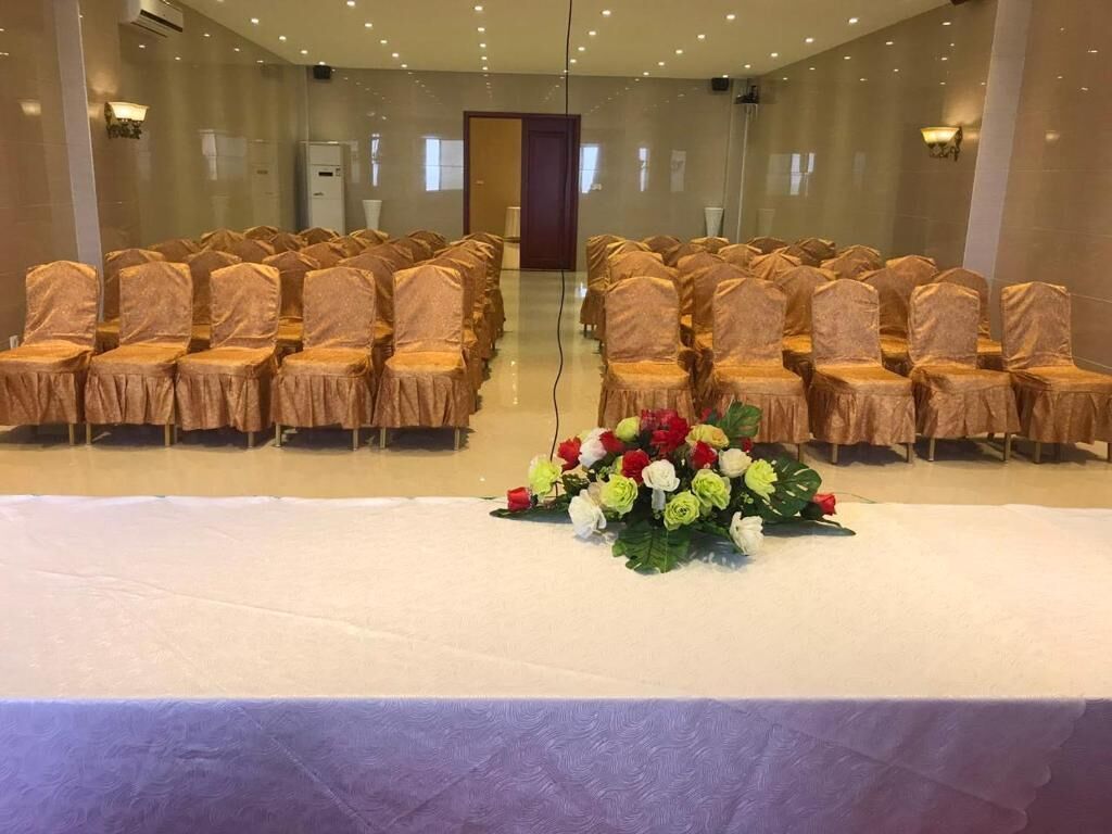 A conference room with rows of chairs, a table with a floral centerpiece, and a door in the background.