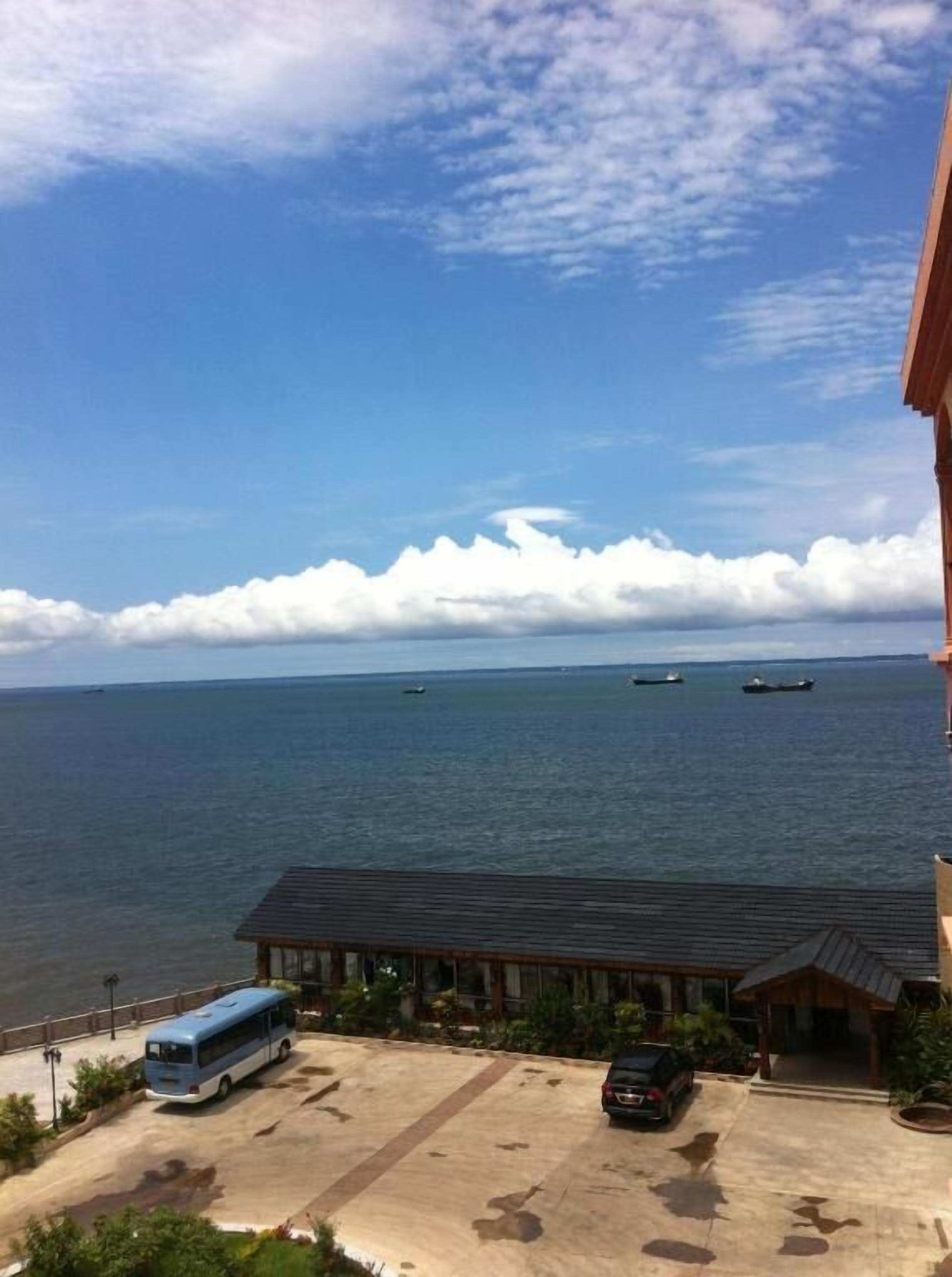 A view of a coastal area with a building, a parking lot, and the sea.