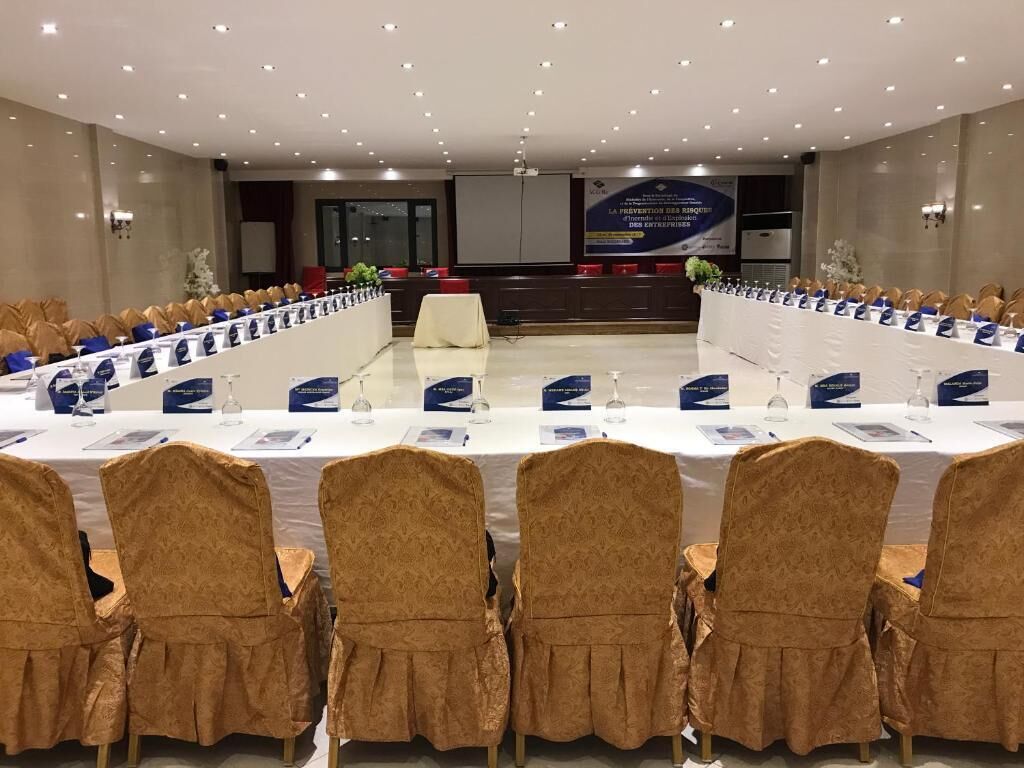 A conference room with a long table, chairs, and a stage.