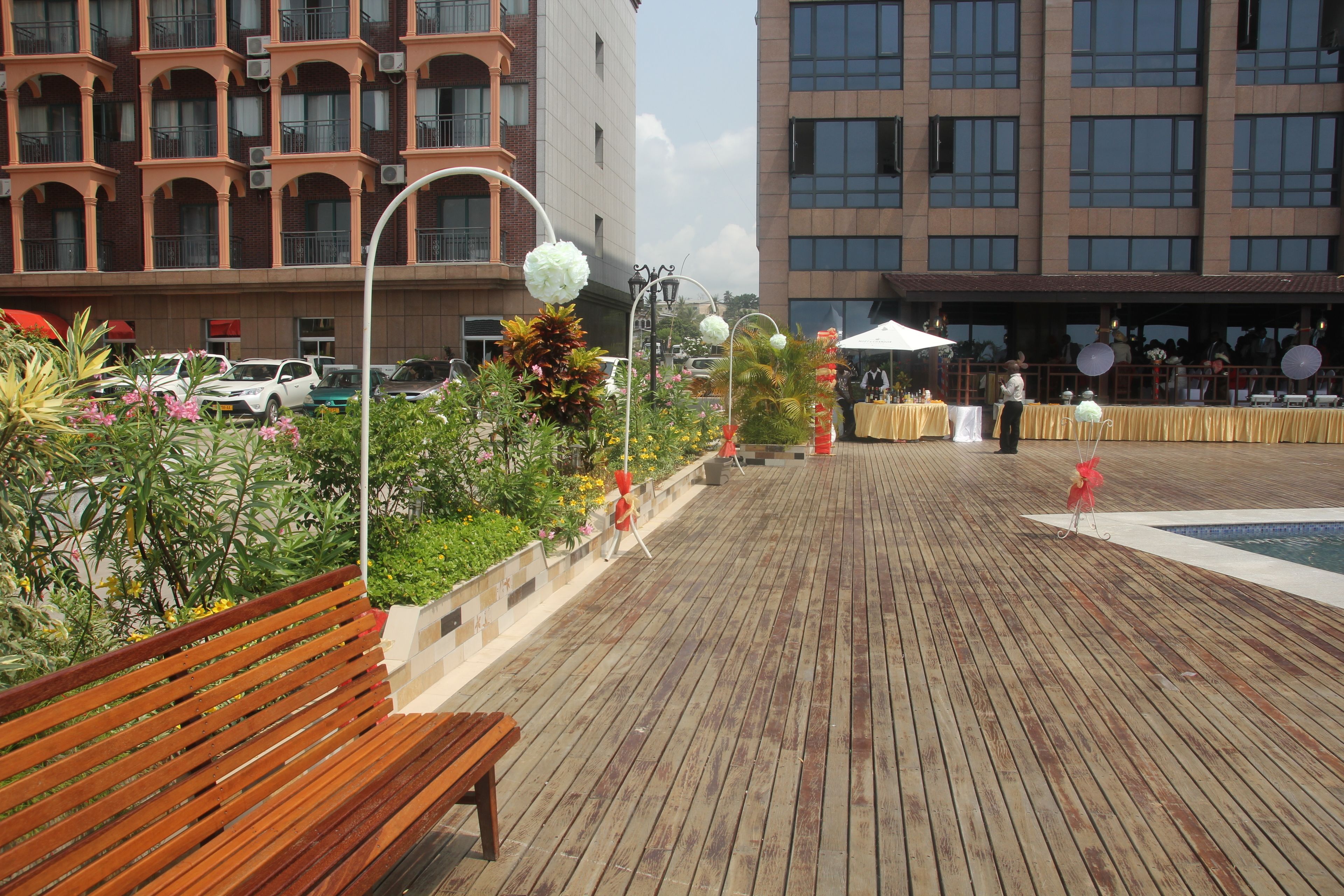 A wooden deck with a bench, surrounded by plants and flowers.