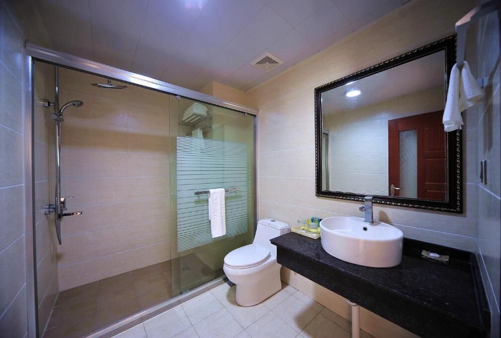 A bathroom with a glass-enclosed shower, a toilet, a sink, and a mirror.