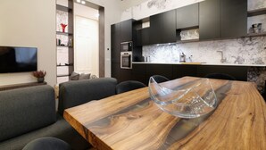 A modern kitchen with dark cabinetry, a marble backsplash, and a wooden dining table with a glass centerpiece. - La Chambre Milano (Milan)