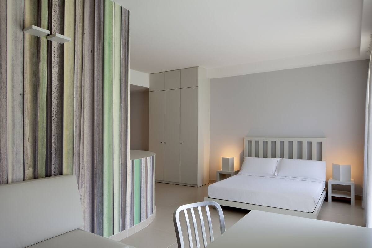 A modern bedroom with a bed, bedside tables, and a wardrobe.