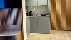 A modern kitchen with grey cabinets, a built-in stove, and a flat-screen TV mounted on a wooden slat wall. - La Chambre Milano (Milan)