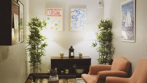 A living room with a sofa, two potted plants, a coffee table, and a rug. - Urban House Hostel (San Sebastián)