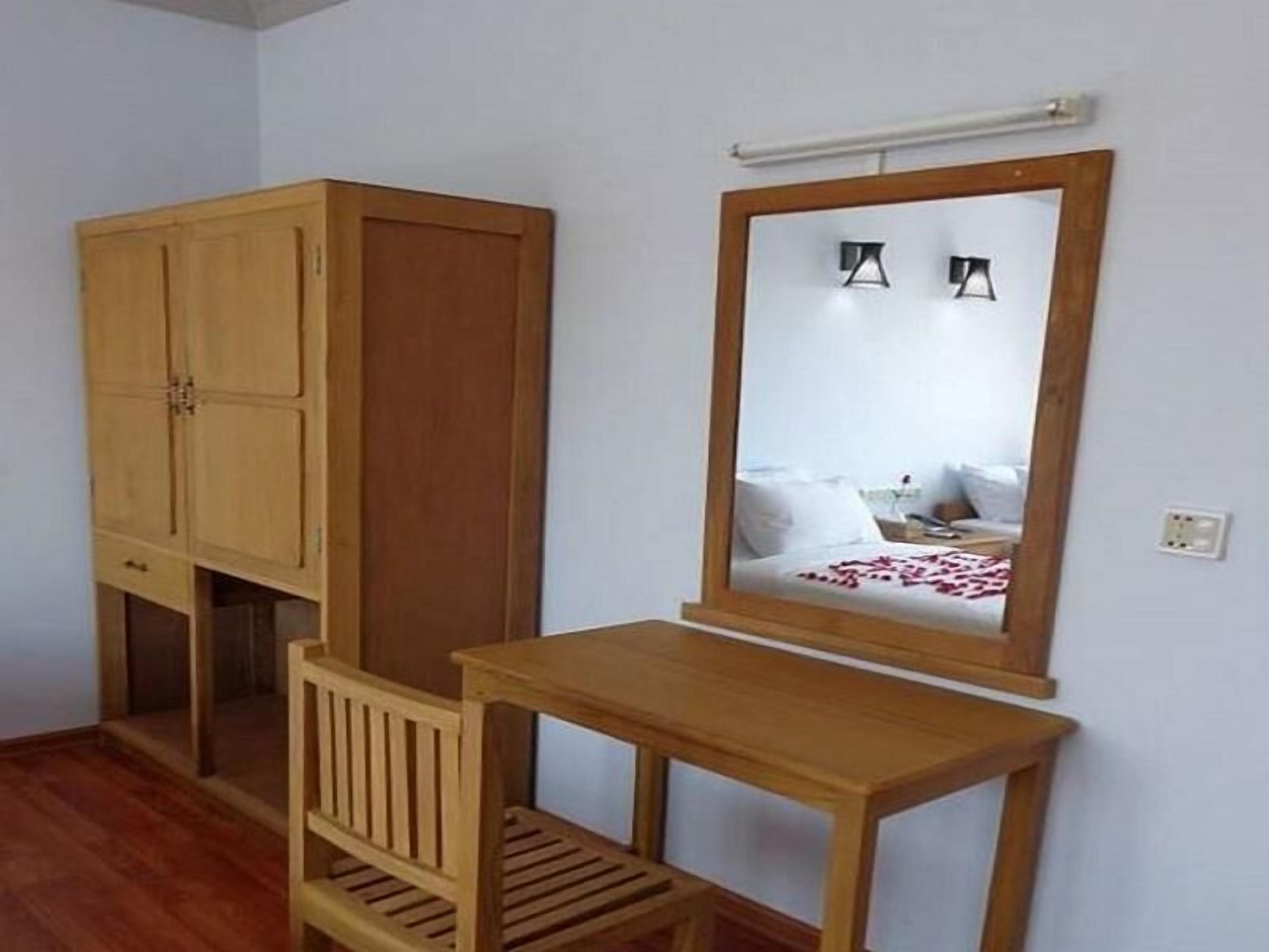 A small room with a wooden wardrobe, a mirror, and a wooden bench.