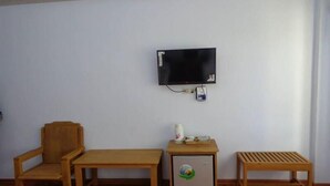 A room with a television mounted on the wall, a wooden chair, a small table with a decorative item, and a bench. - Golden Lotus Inle Hotel (Nyaungshwe)