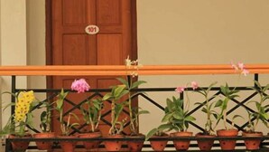 A wooden door with a number plate, a balcony railing, and potted plants. - Golden Lotus Inle Hotel (Nyaungshwe)