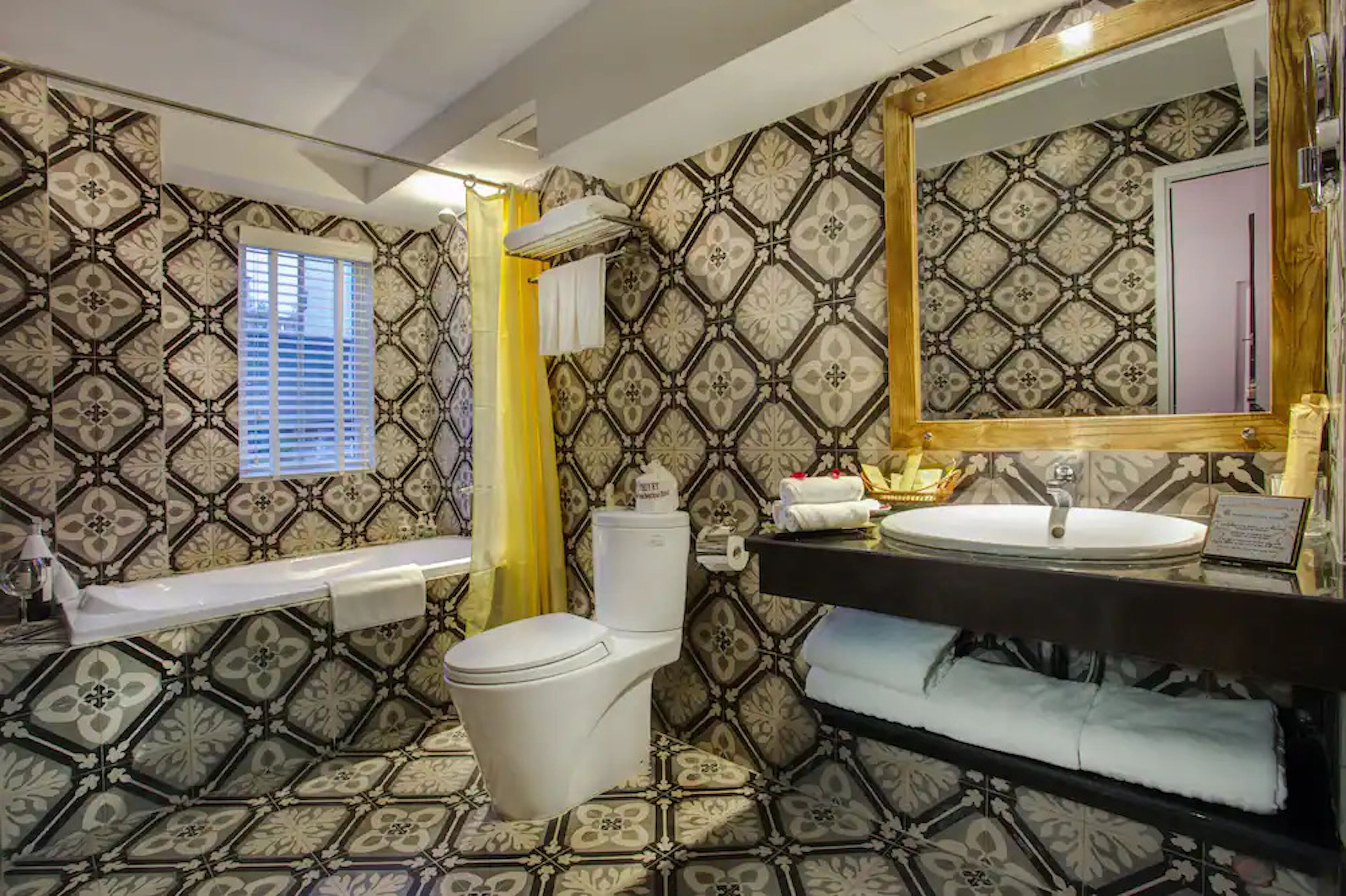 A bathroom with patterned wallpaper, a toilet, a sink, and a mirror.