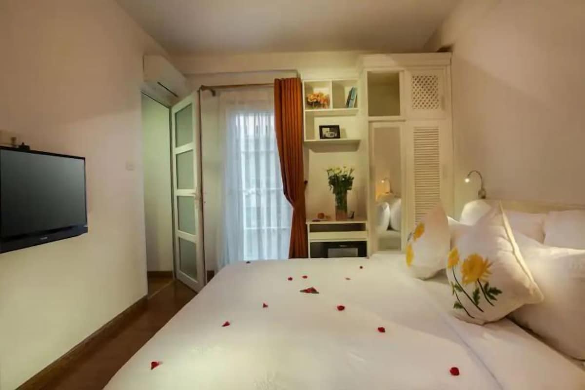 Una habitación de hotel con cama, televisión, escritorio y armario.